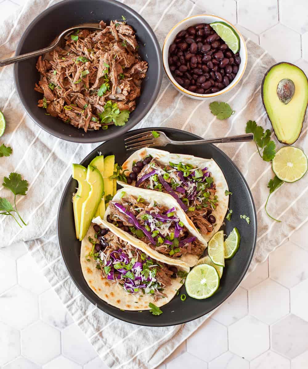 Our Instant Pot Shredded Beef Tacos are perfect for Taco Tuesdays or meal prep on Sundays! This simple shredded beef cooks up juicy and flavorful in the pressure cooker and can be used for many recipes besides tacos. | MarathonHandbook.com #instantpot #pressurecooker #beef #tacos