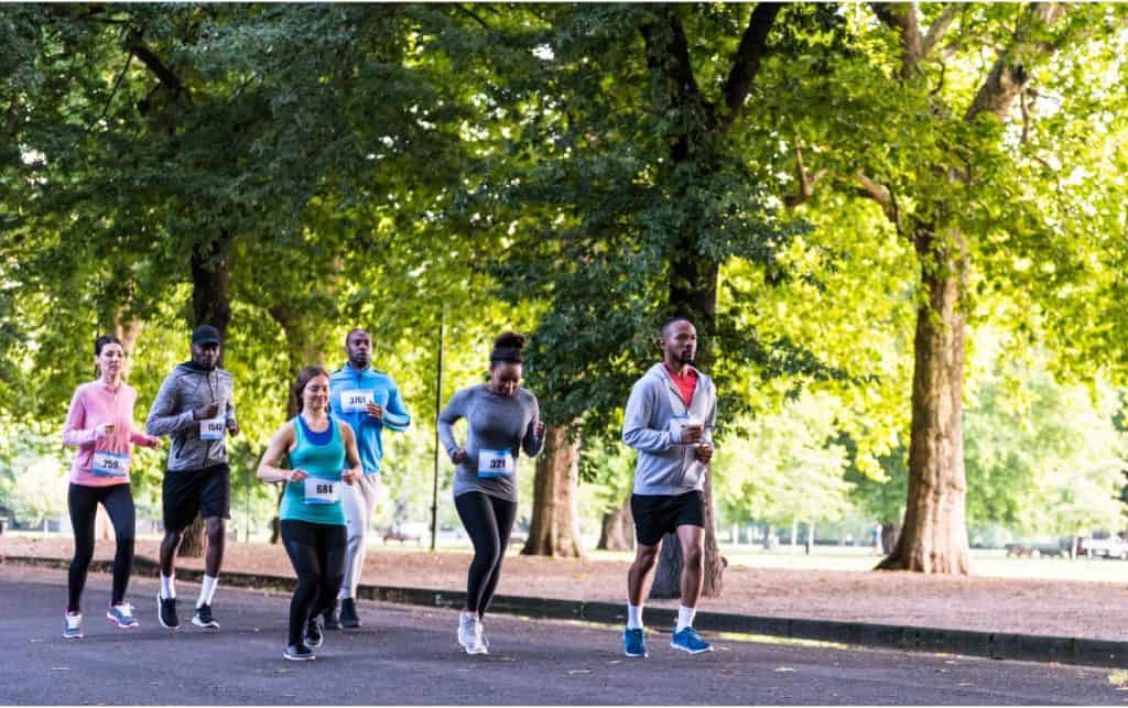 A group of people running on a road in front of some trees