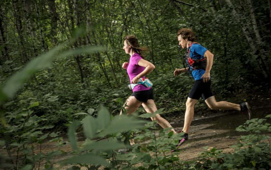 un hombre y una mujer corriendo en el bosque