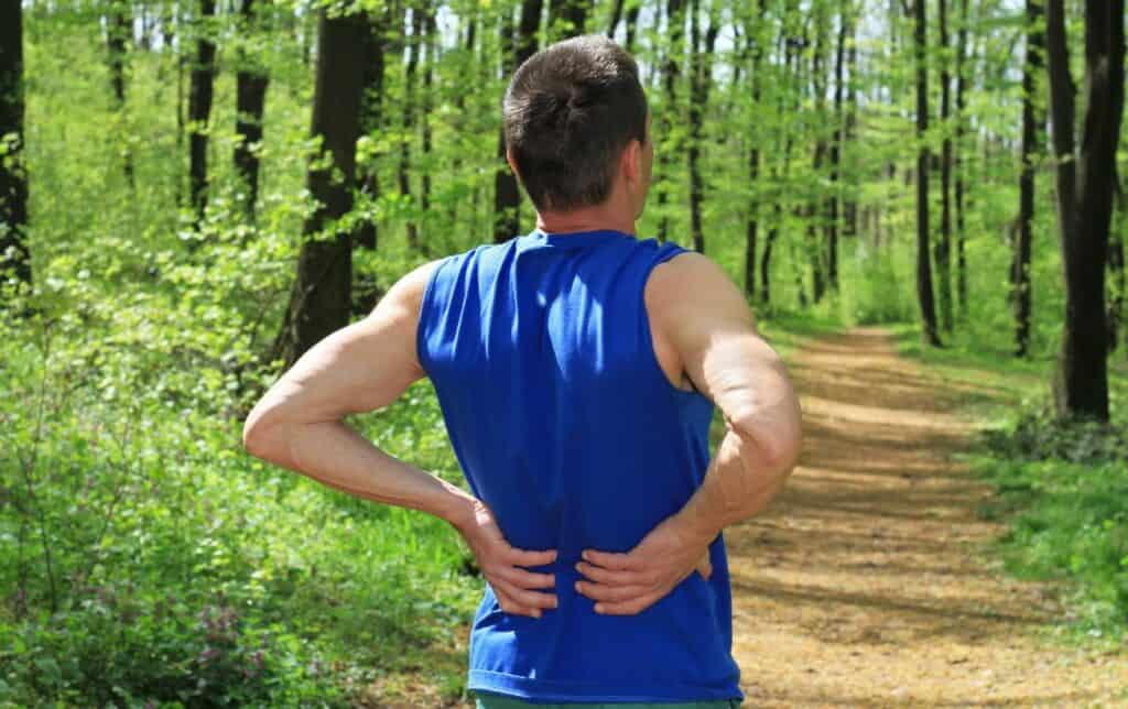 A man in the woods with lower back pain while running.