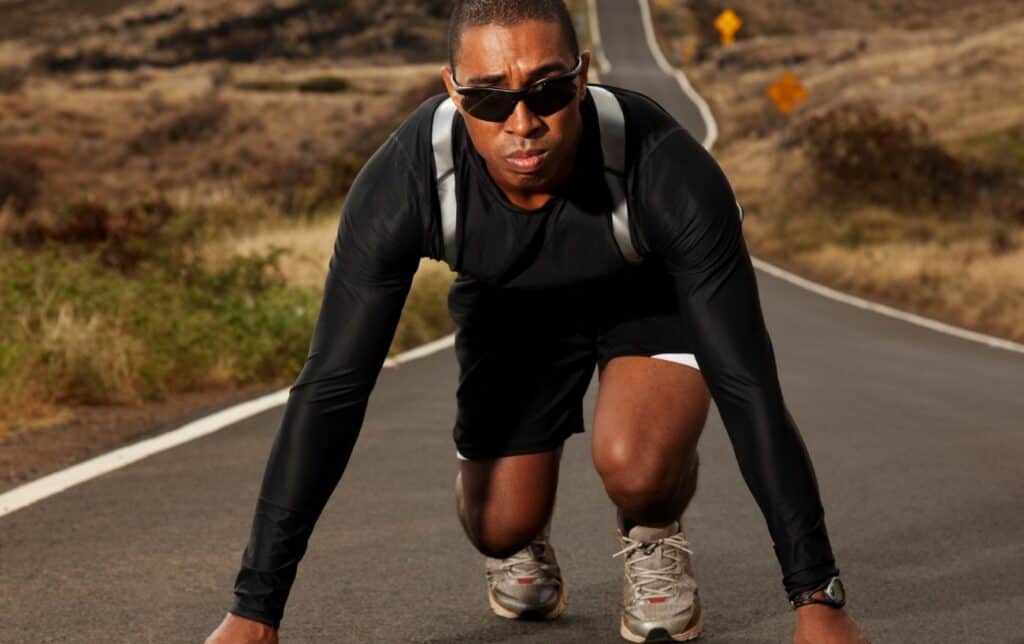 un hombre con gafas de sol en la posición de salida de una carrera en un camino en la naturaleza