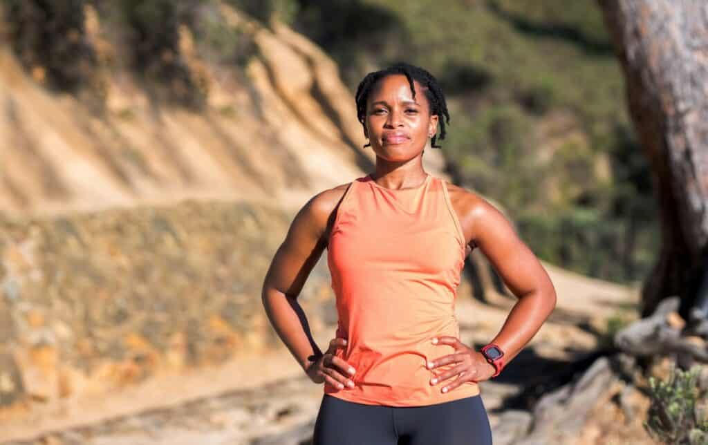 Una mujer con equipo de correr con las manos en las caderas en un cañón