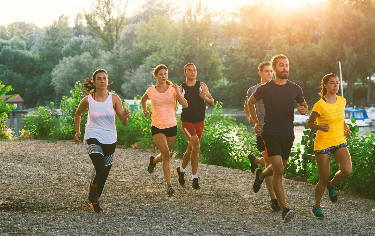 group of runners running alongside a riverbank