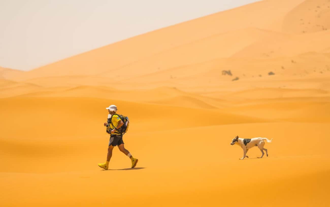 a marathon runner with his dog running in desert
