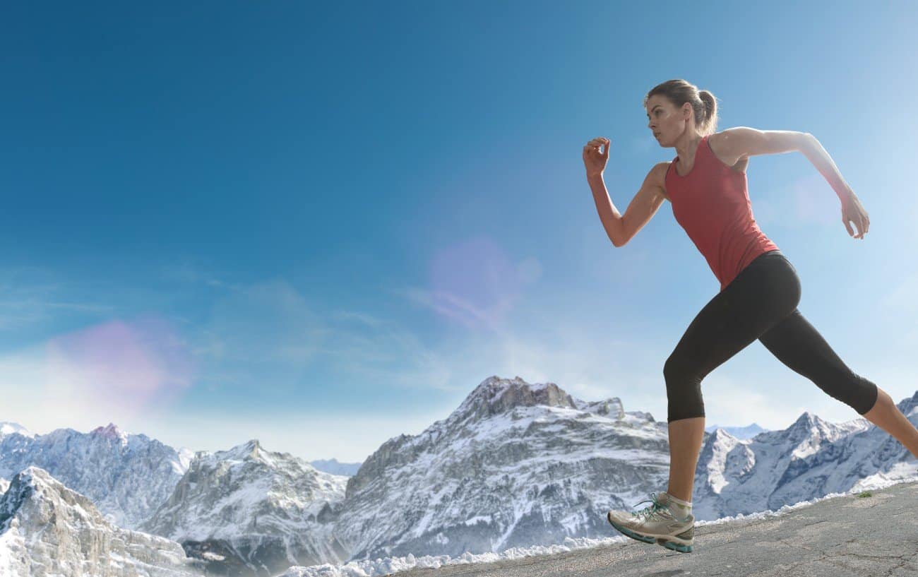 una mujer corriendo junto a montañas nevadas