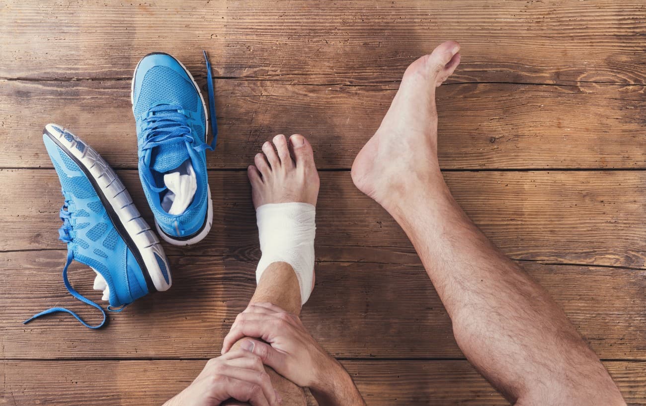 Pies descalzos junto a zapatillas para correr azules en un piso de madera.