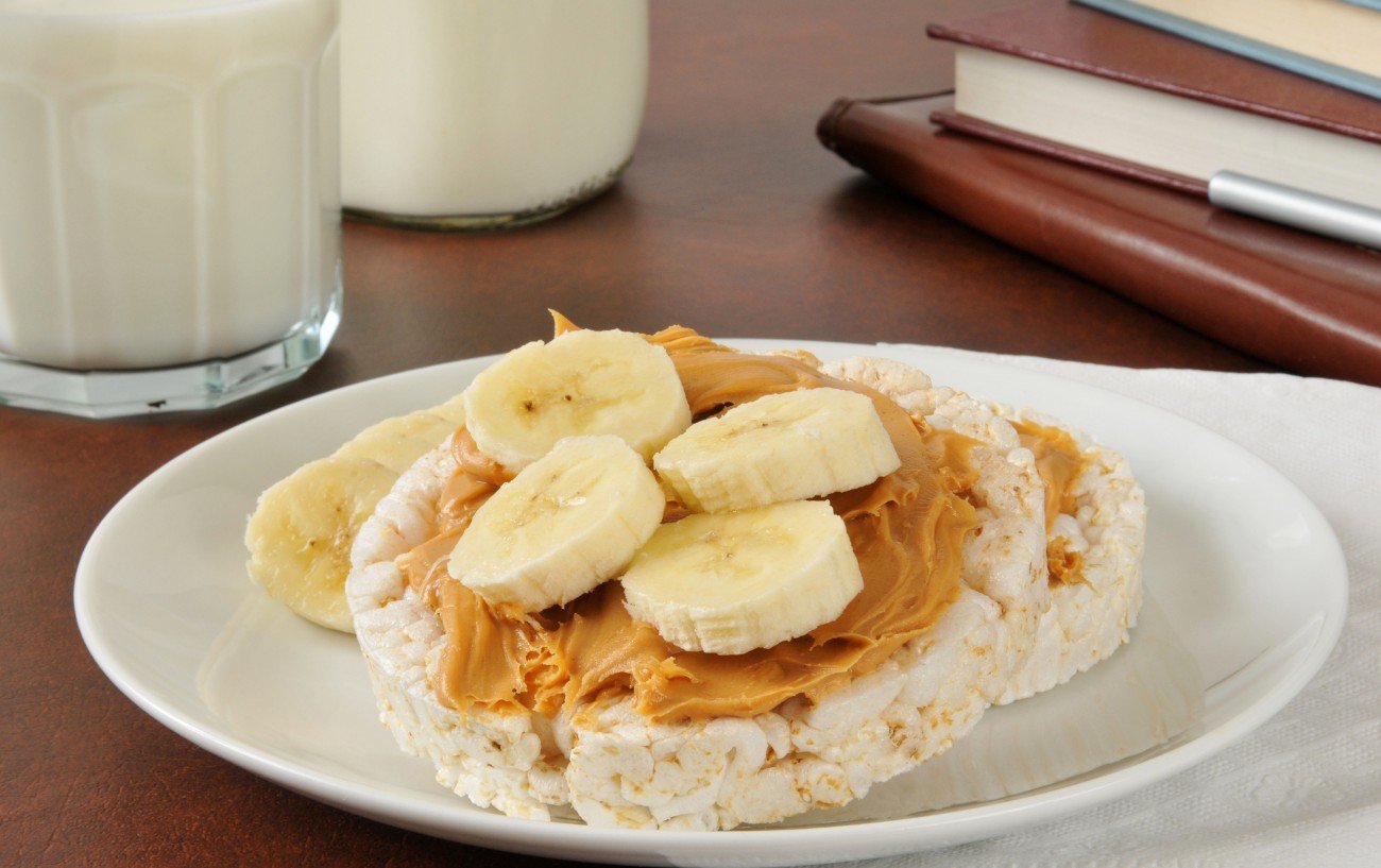 Un plato de galletas de arroz con mantequilla de maní y plátano encima