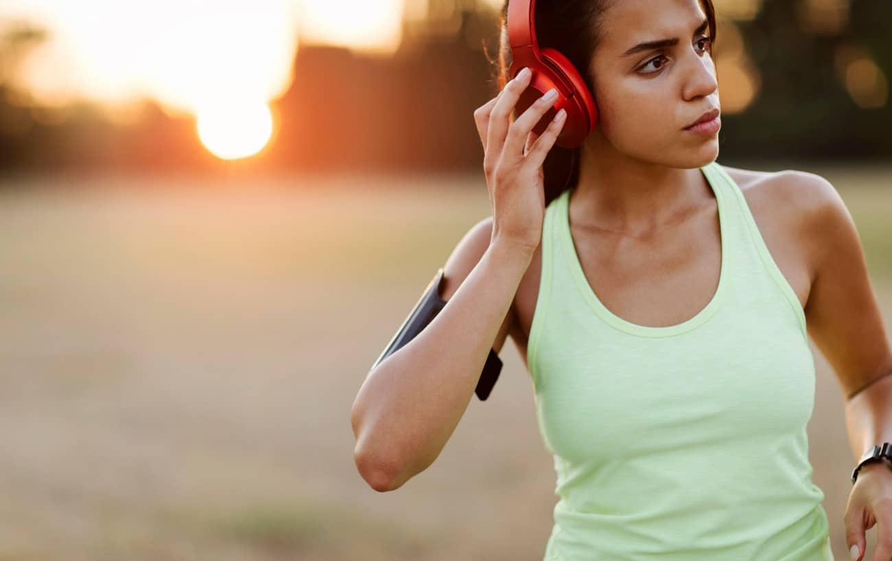 A woman adjusting her headphone while running.