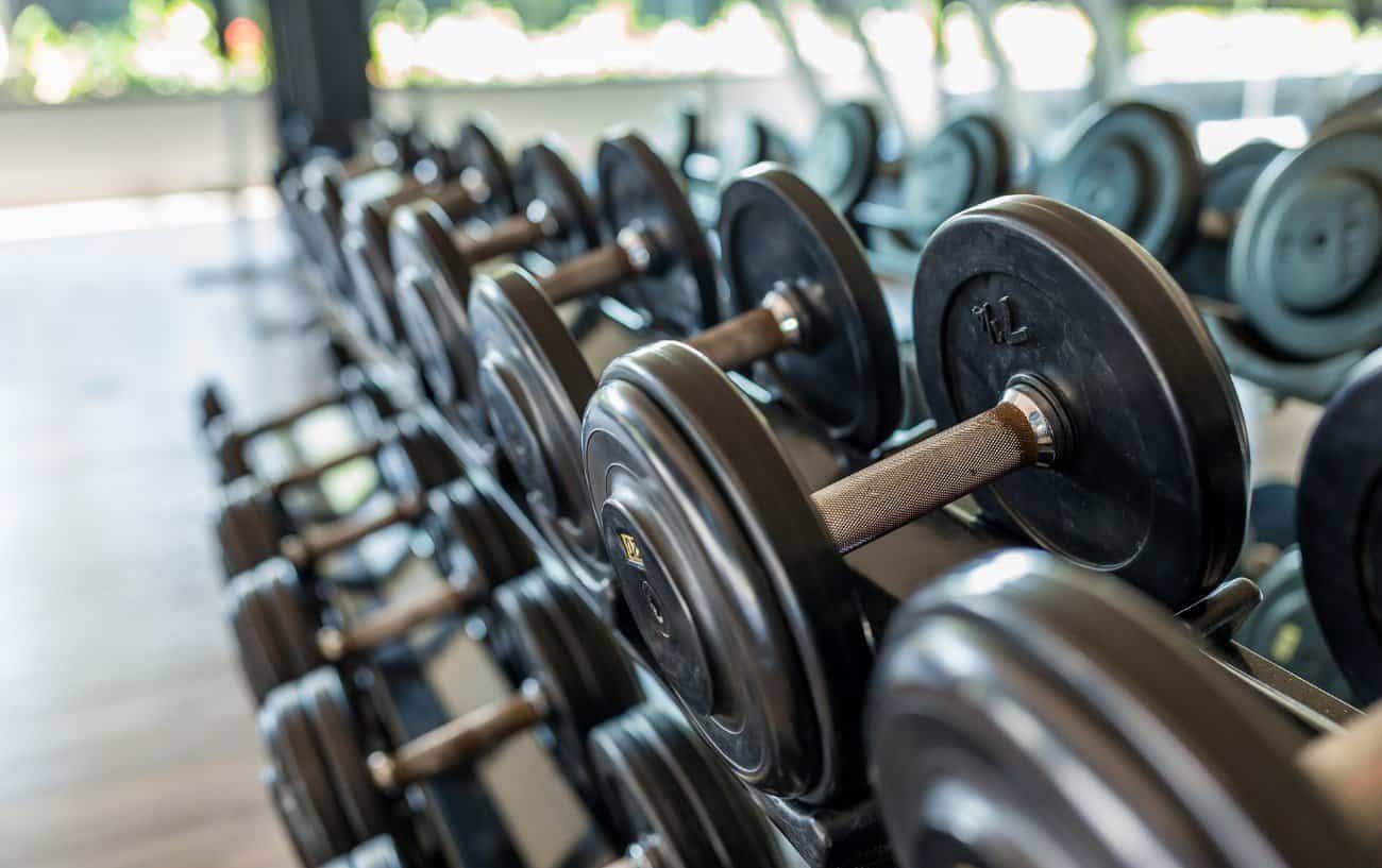 Un primer plano de un estante de mancuernas en un gimnasio.