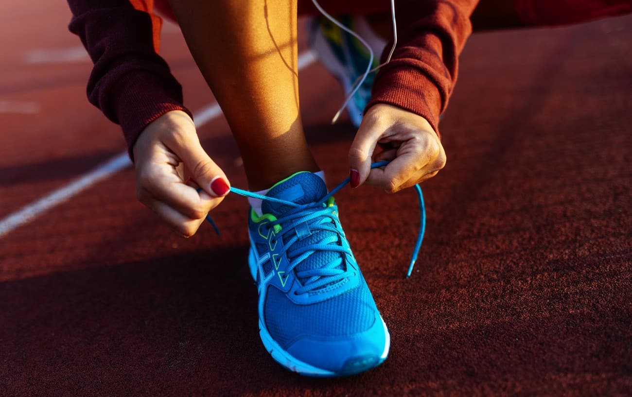 A person tying their blue running shoe.