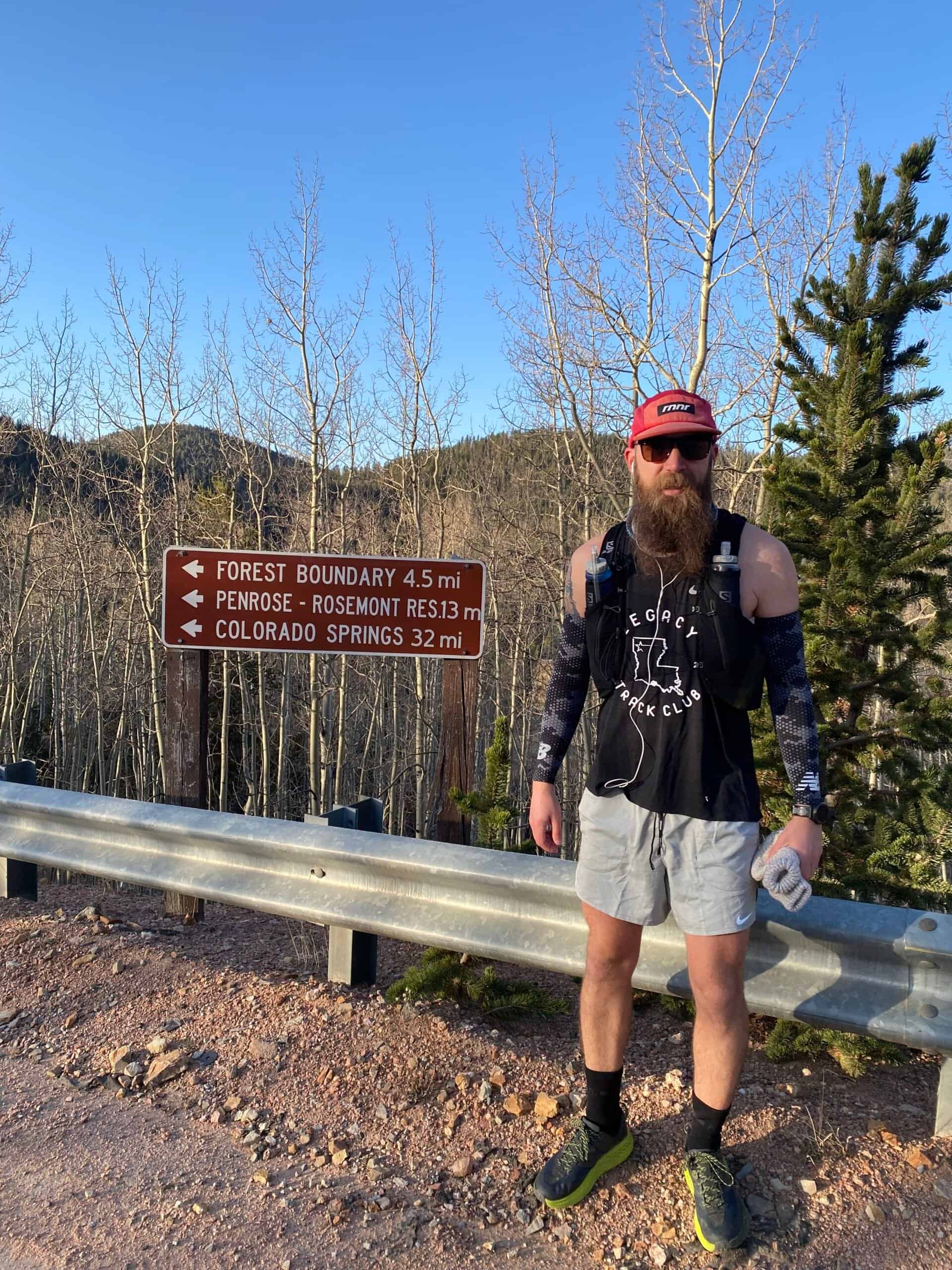 Adam en su ruta FKT junto a un letrero de carretera.