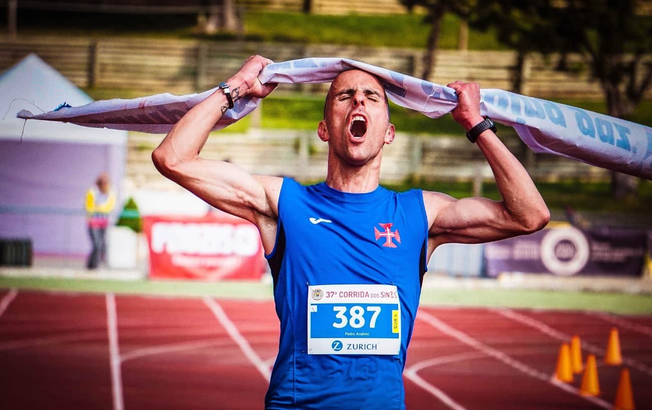 A man running through the finish line on a track.