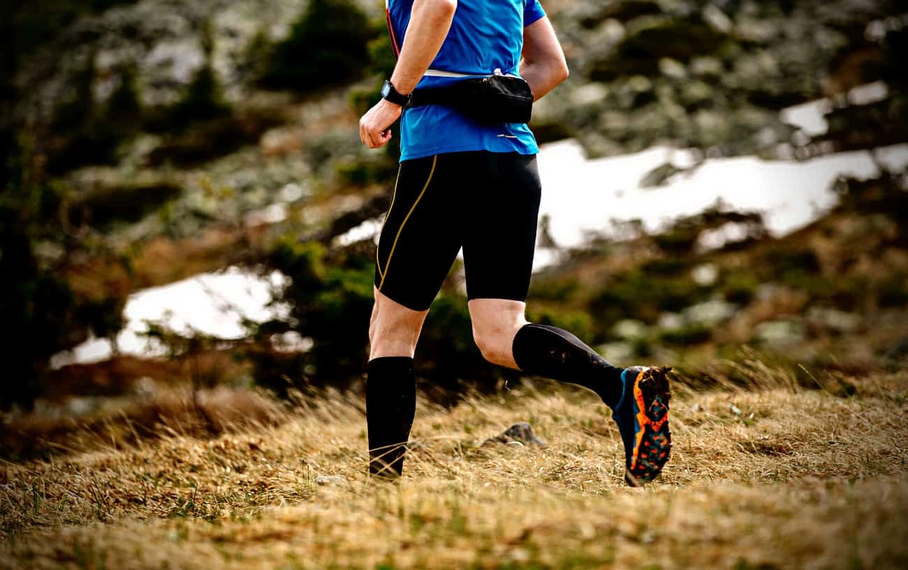 male runner in compression calf sleeve running forest trail Stock