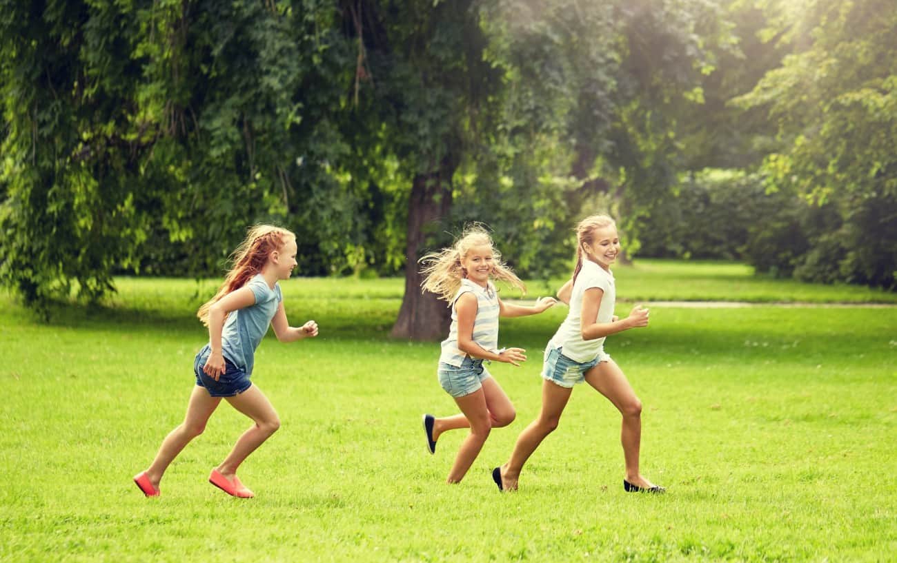 3 niños corriendo en un campo.