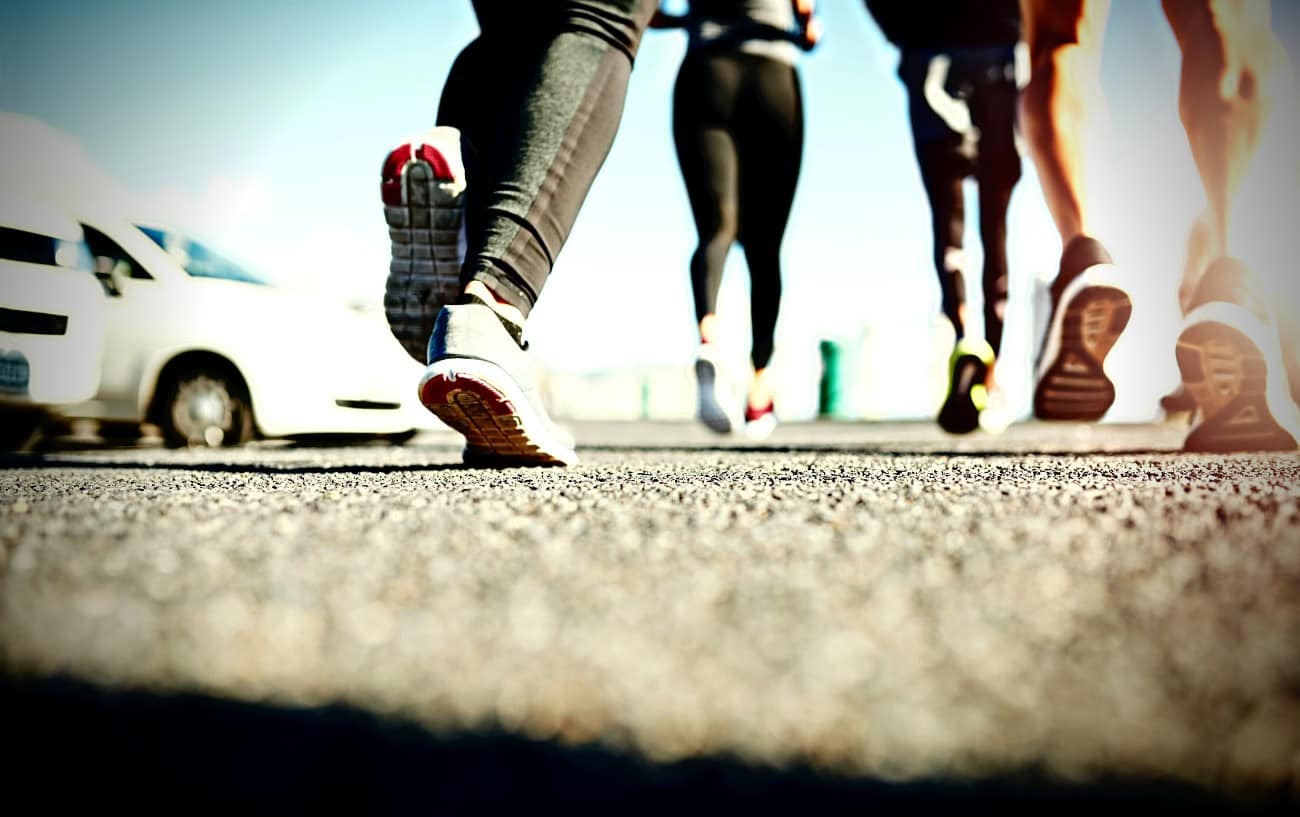 A close-up of the back of people's shoes as they run.