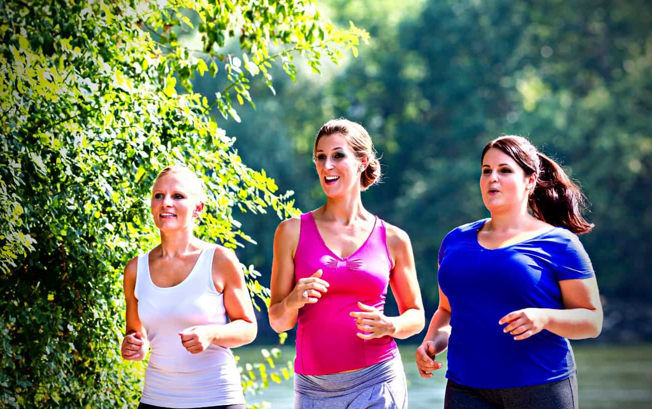 Three people smiling as they run.