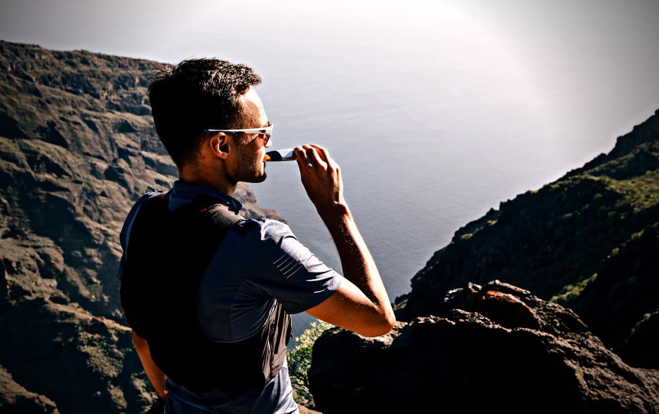 Una persona comiendo un gel energético en un acantilado.