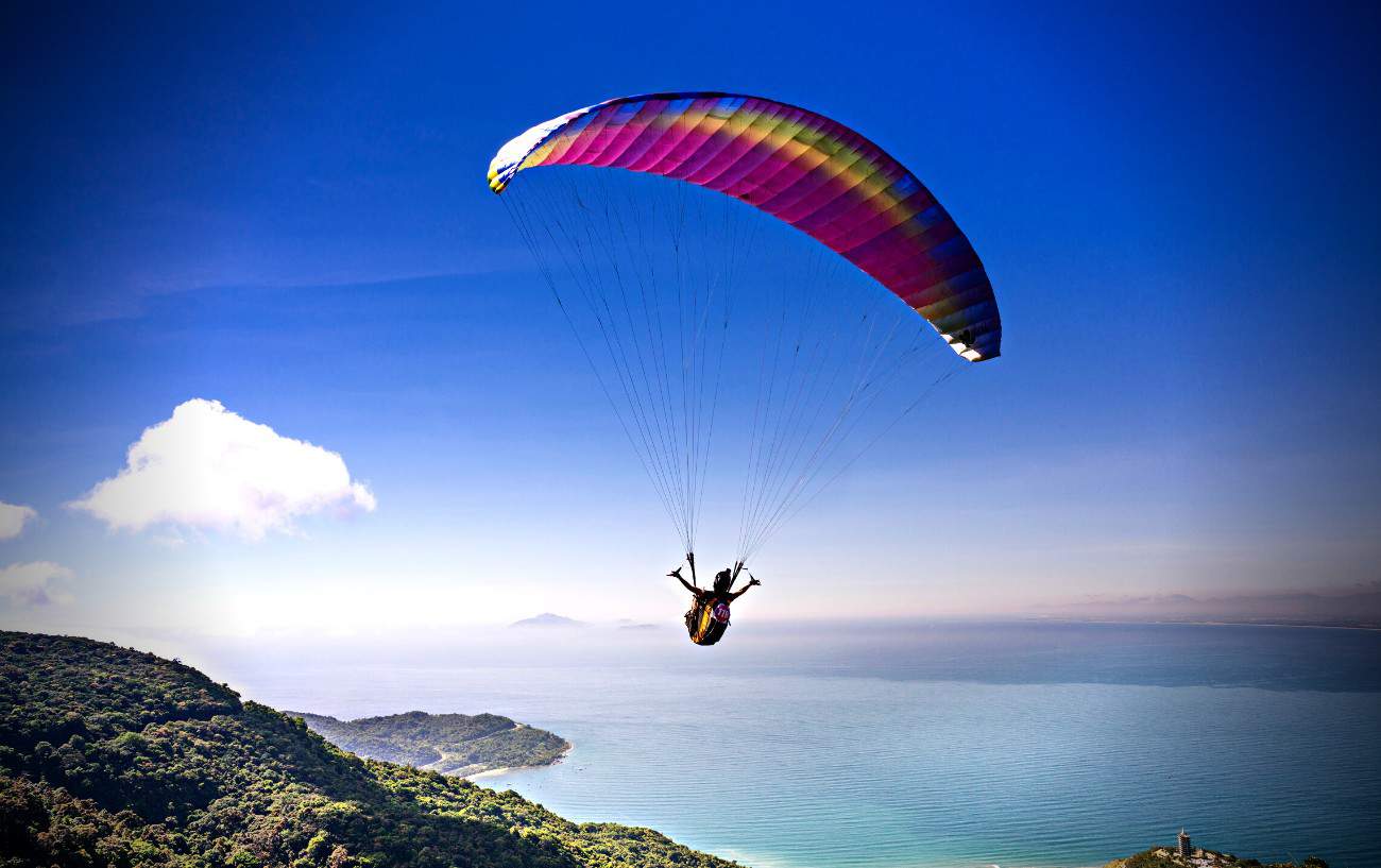 A person paragliding over the ocean.