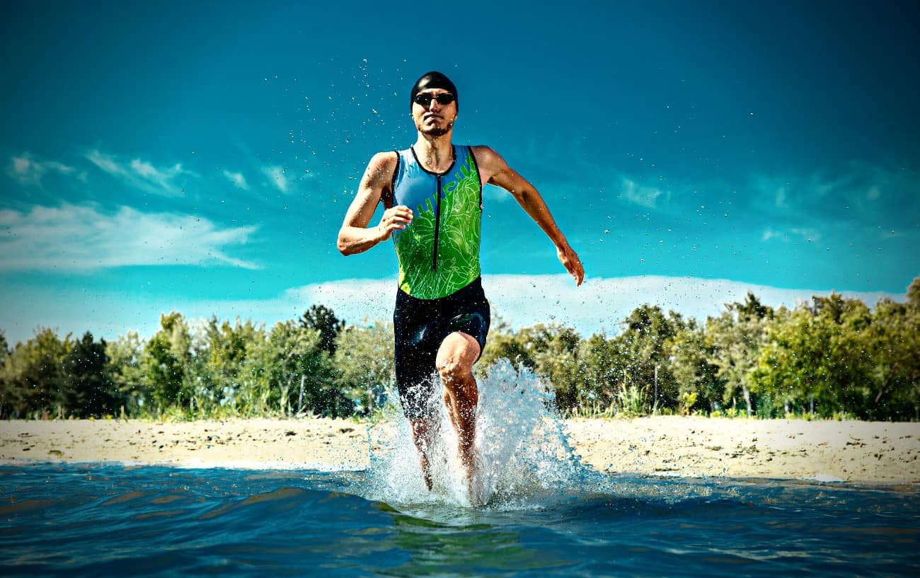 Una persona corriendo hacia el océano en un traje de triatlón.