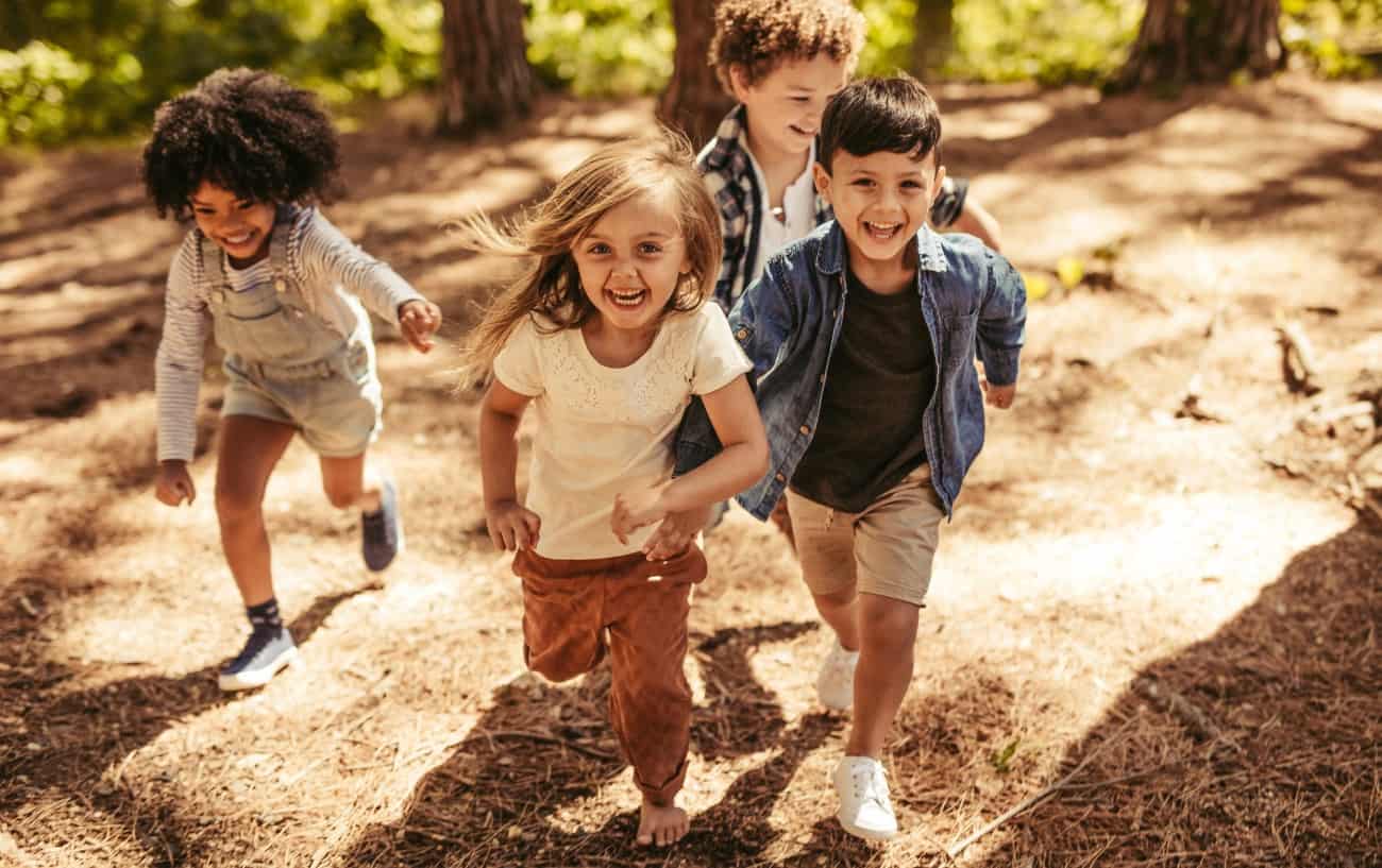 Four children running around in the forest.