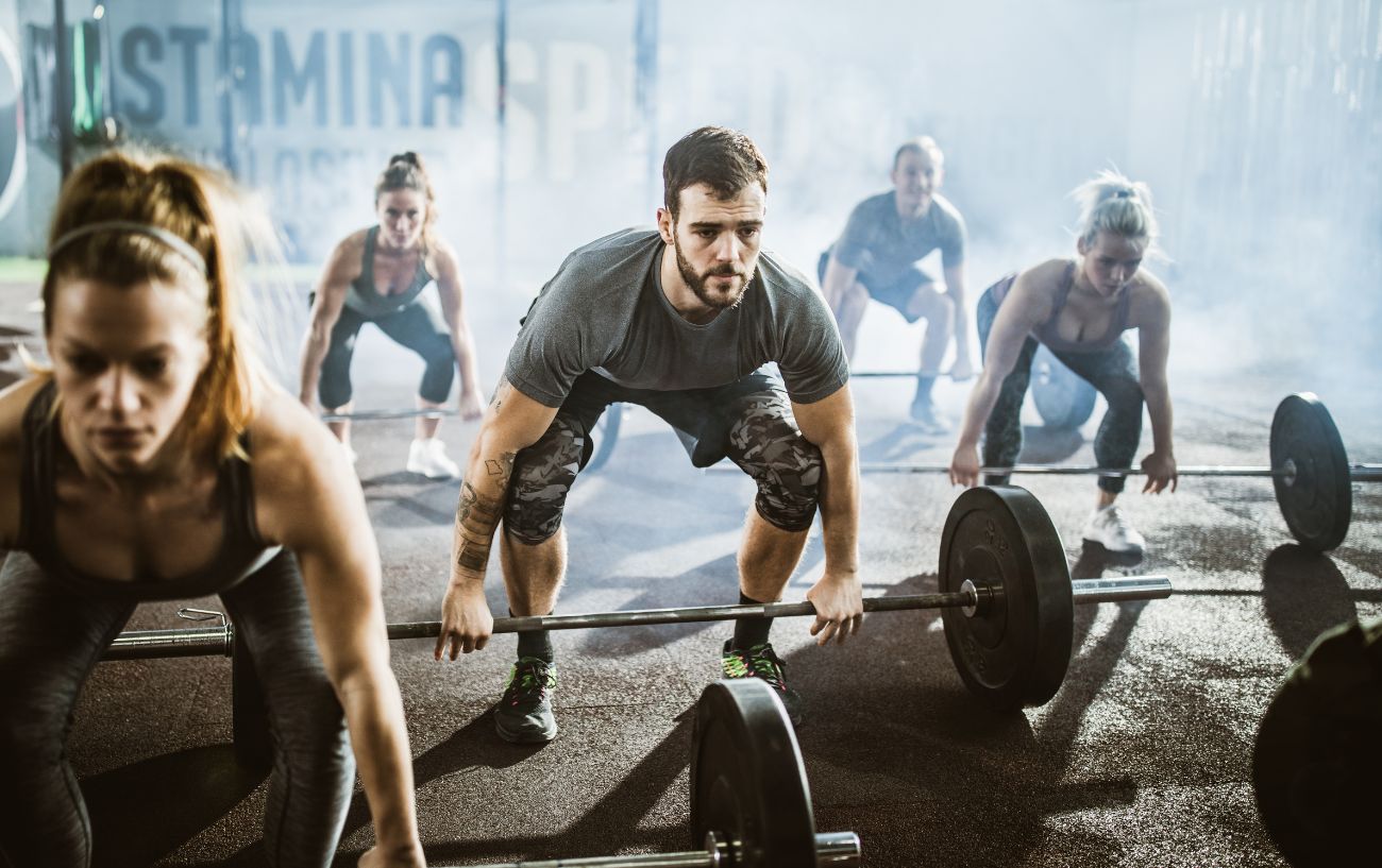 Personas en un gimnasio haciendo peso muerto.