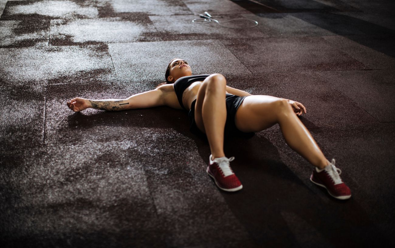 A person feeling lightheaded after a workout exhausted on the ground.