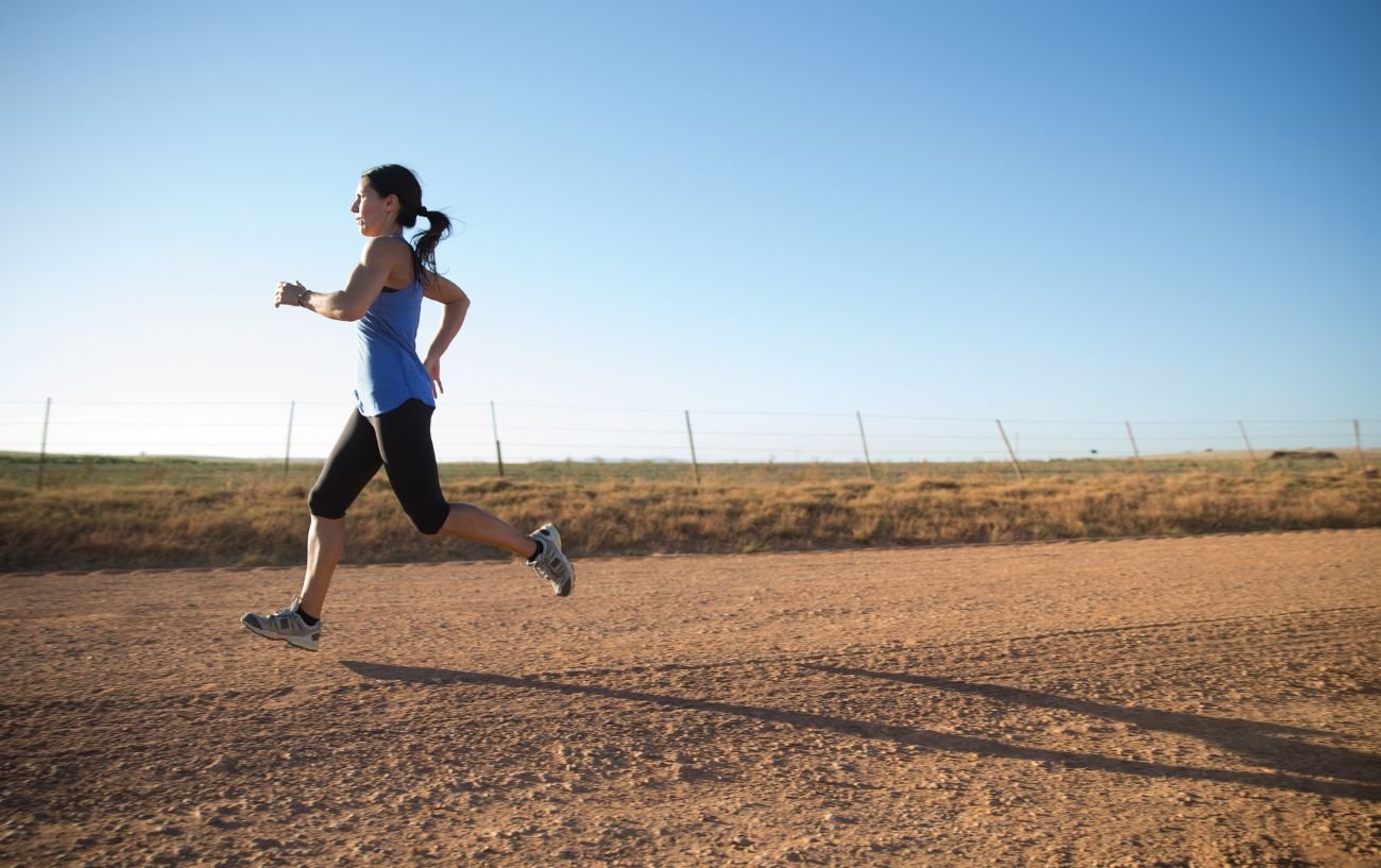 A person running fast on a dirt road.