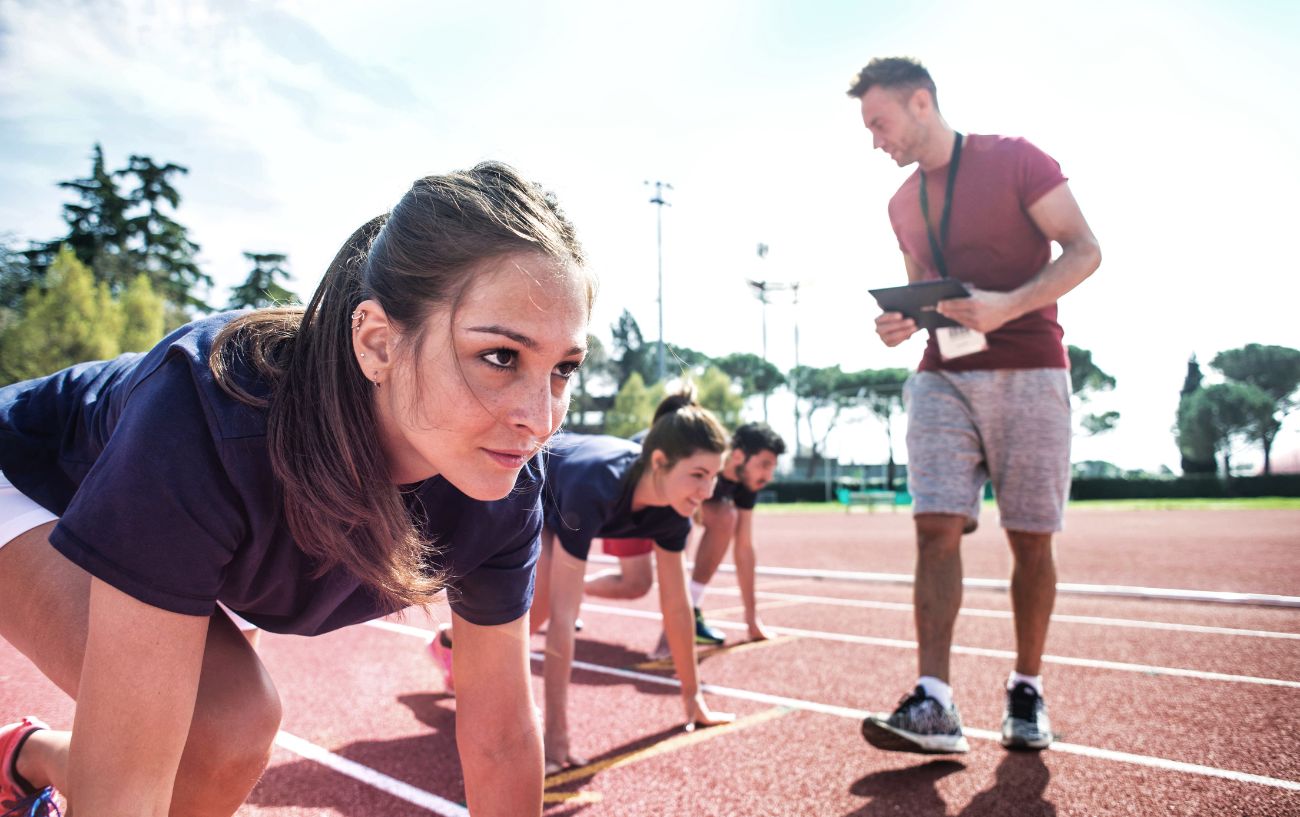 Un entrenador de running con corredores en una pista.