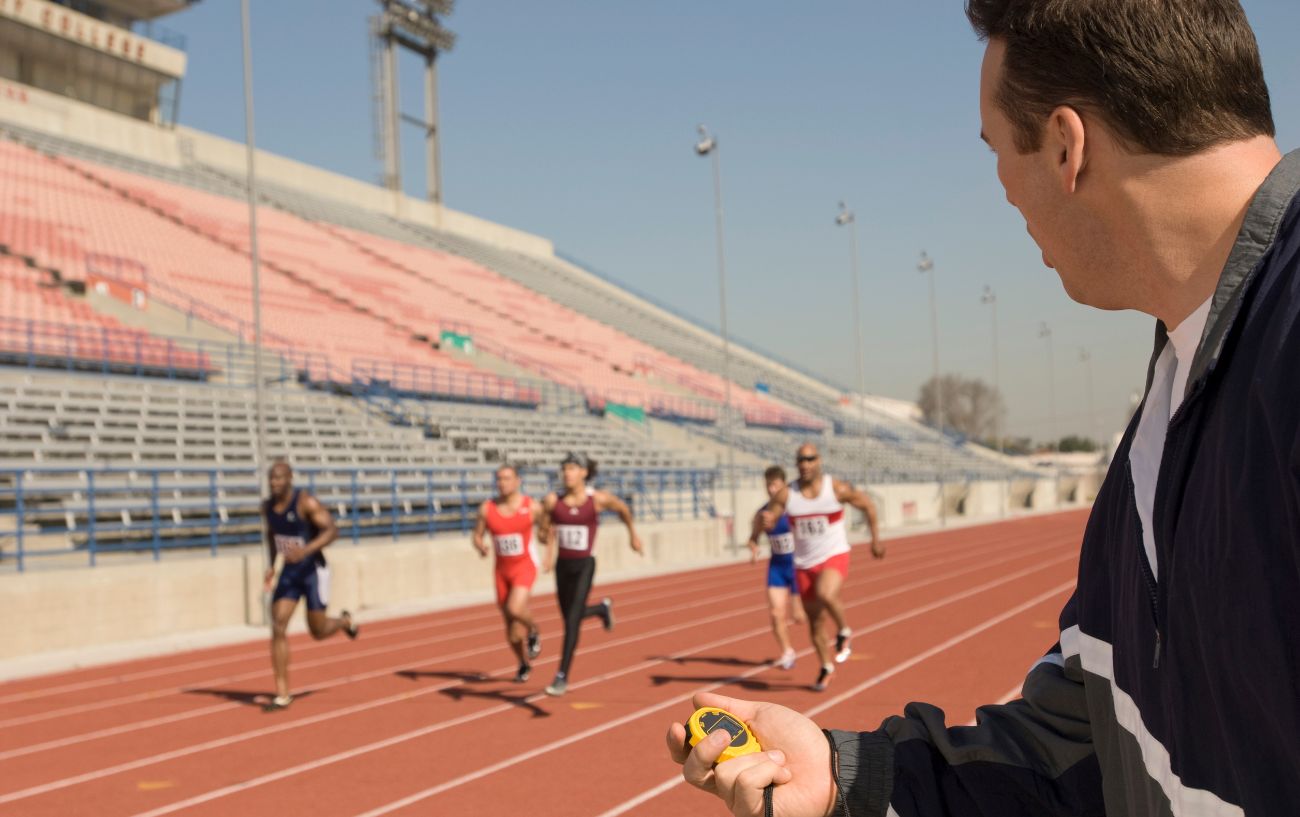 Un entrenador de running con corredores en una pista.