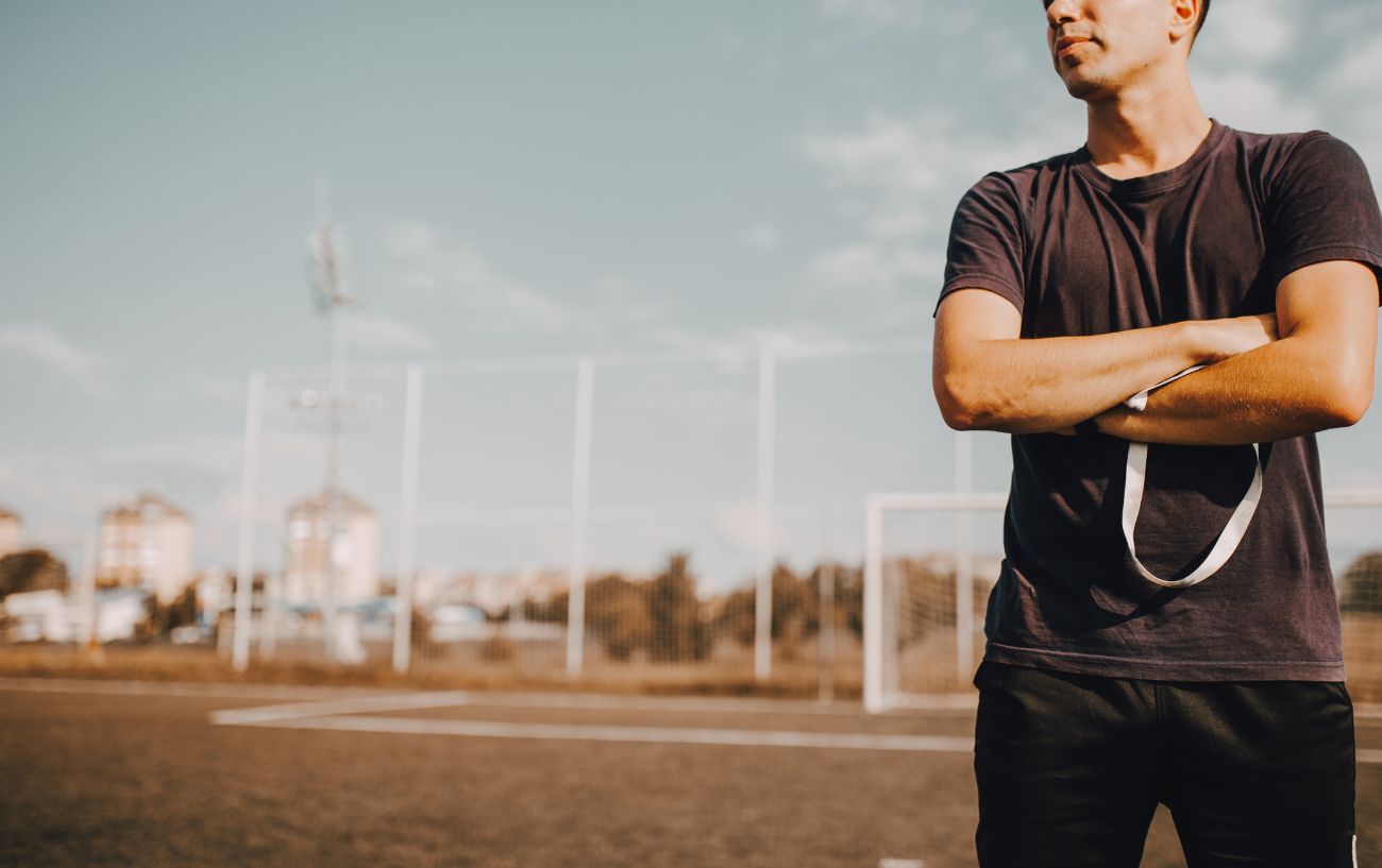 Un entrenador de running en una pista con los brazos cruzados.