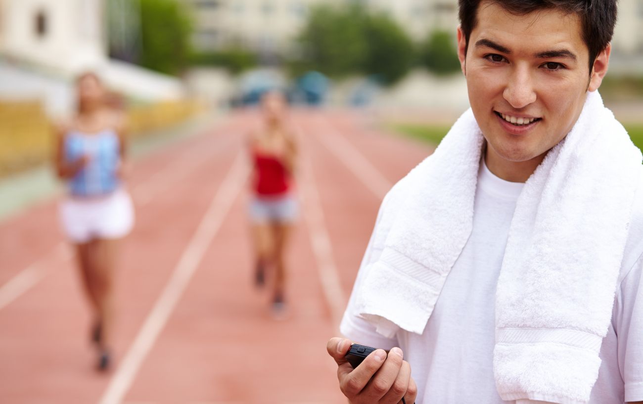 Un entrenador de running en una pista con corredores.