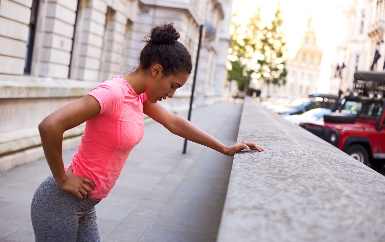 A tired runner leaning against a wall.