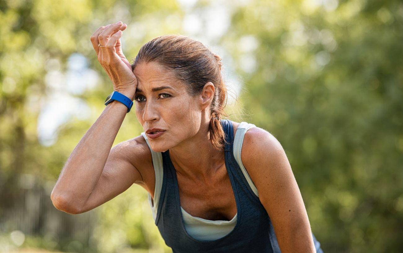 A sweaty tired runner with a hand on their face.