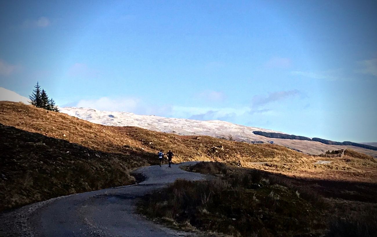 Two trail runners running on an open path.