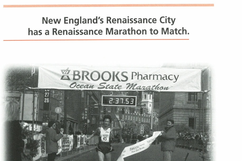 A runner crosses the finish line at the Brooks Pharmacy Ocean State Marathon, clock showing 2:37:53.