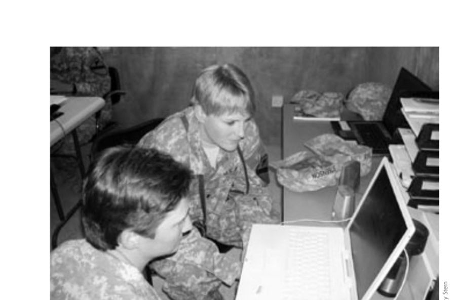 Staff Sergeant Christine Cooper (in foreground) and First Lieutenant Sara Day plot out transportation logistics in their makeshift Army office at Camp Liberty in Baghdad.