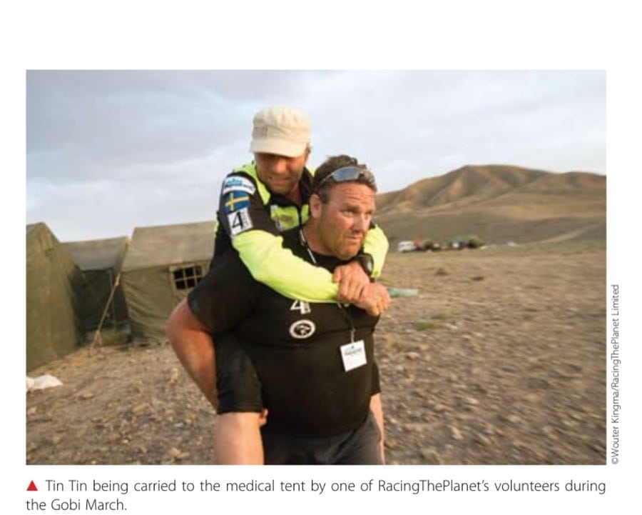 Tin Tin being carried to the medical tent by one of RacingThePlanet's volunteers during the Gobi March.