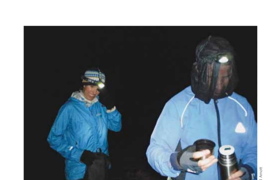 Running The Ramsay 18 After 15 hours of mountain running, the author takes a 10-minute tea break at Fersit Dam; John Hepburn wears a head net because of formidable midges.