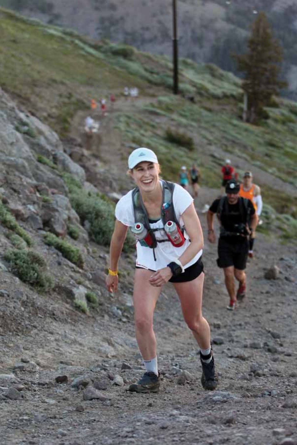 The Importance of Race Diet During a 100-Mile Ultramarathon 42 A smiling female ultramarathon runner ascends a rocky mountain trail during a race. © Joe McCladdie