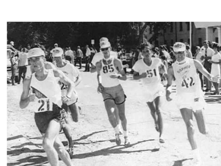 William Clark-led group shown beginning their third 5.2-mile loop. Left to right: Capt. William Clark, USMC, [hidden behind him is Frank Shorter whose one leg can be seen], unknown runner, Amby Burfoot (85), George Husuark (51) of Montebello, California, and Tom Heinonen (42) of Minneapolis.