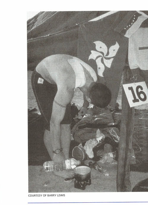 Some people carried stoves for food preparation, while others relied on the heat of the sun. Here Mark Sharp prepares water for tea at the end of a stage. Preventive bandages help alleviate the blisters that have developed from his pack rubbing his back.