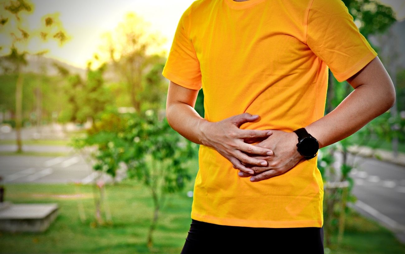 Una persona sosteniendo su costado debido a un calambre abdominal.