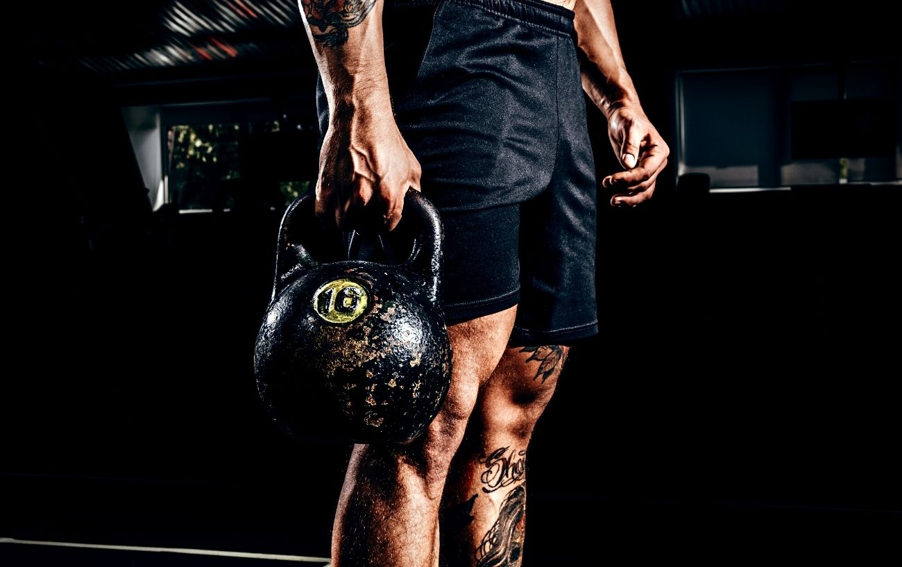 The Ultimate Beginner Kettlebell Workout: 5 Great Kettlebell Exercises For Beginners 7 A person holding a kettlebell on one side to do a farmer's carry.