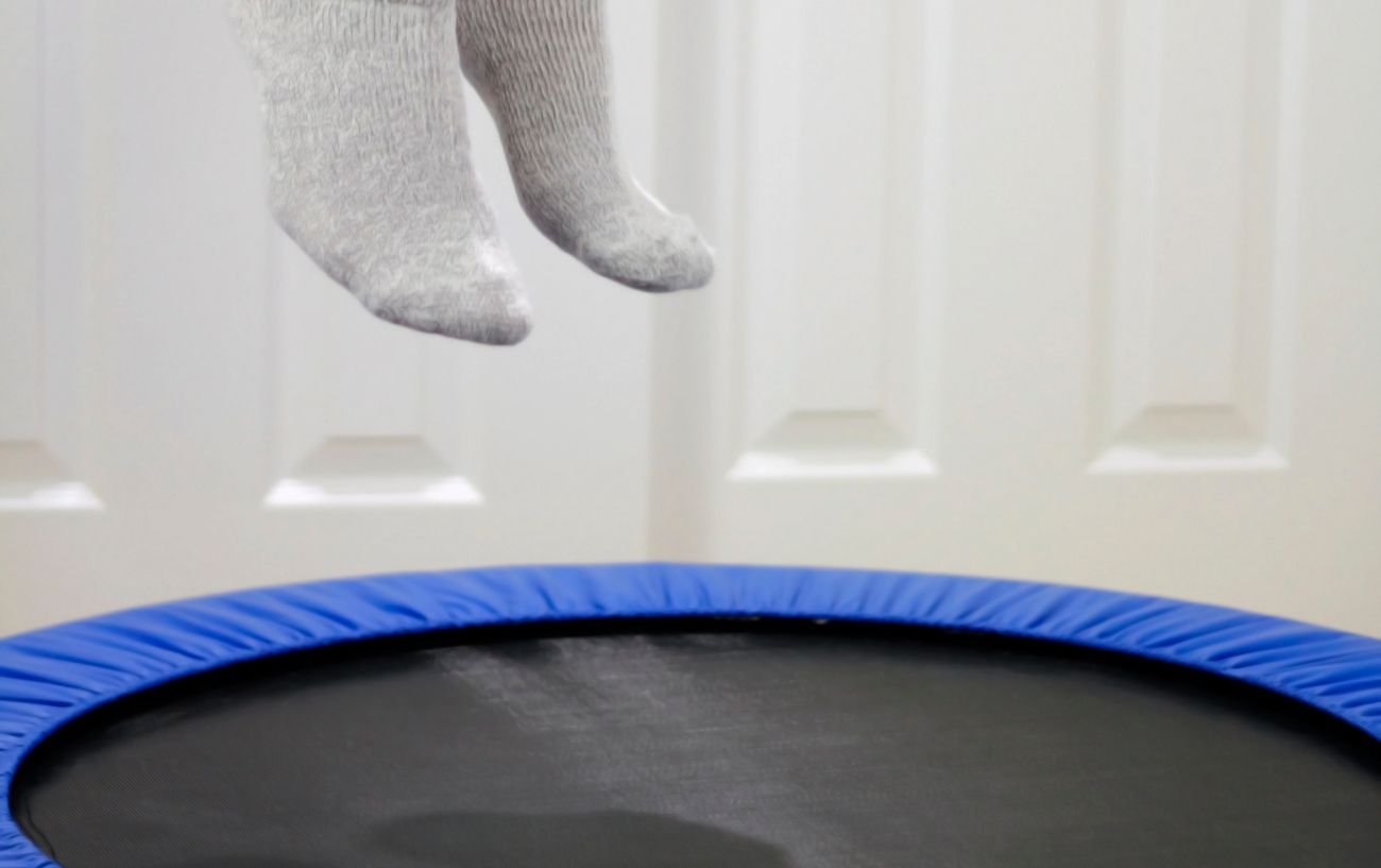 Un primer plano de pies en el aire justo sobre un trampolín.