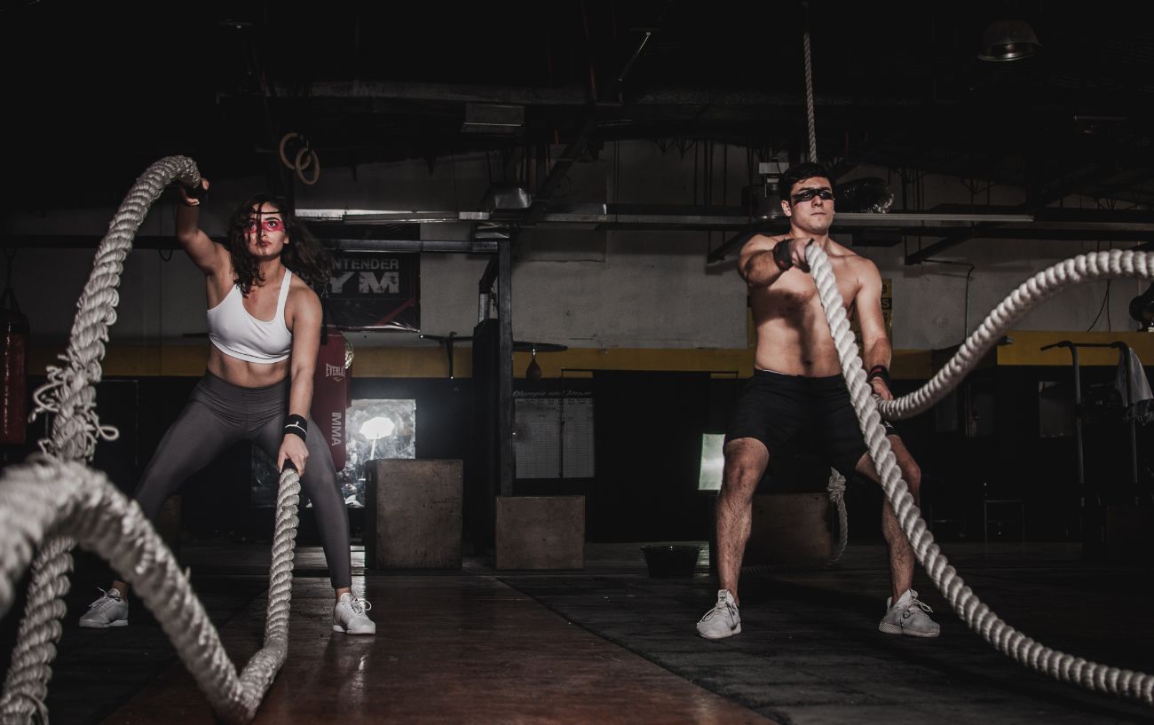 Two people doing battle ropes at the gym.