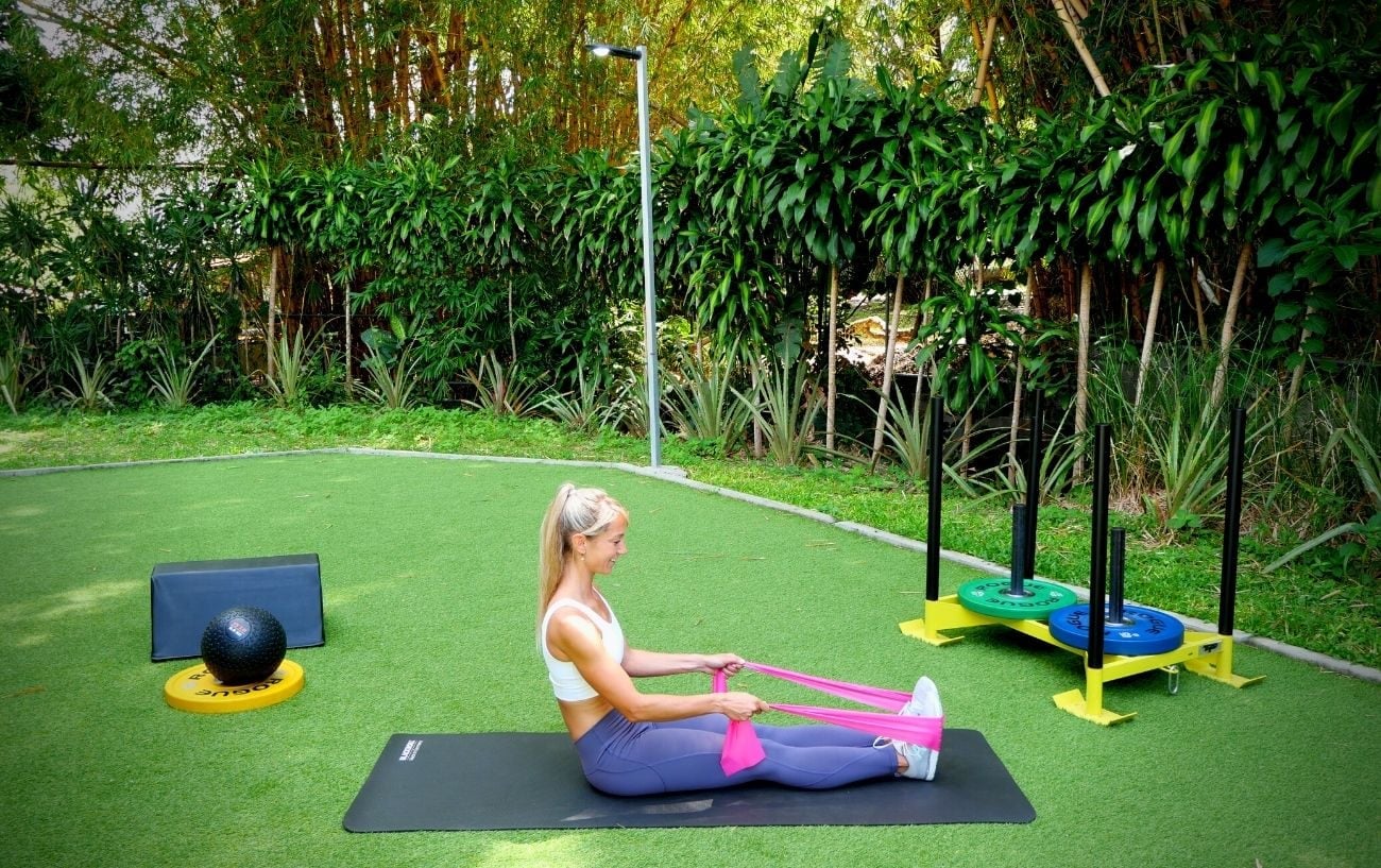 a woman sitting on a mat with a pink band