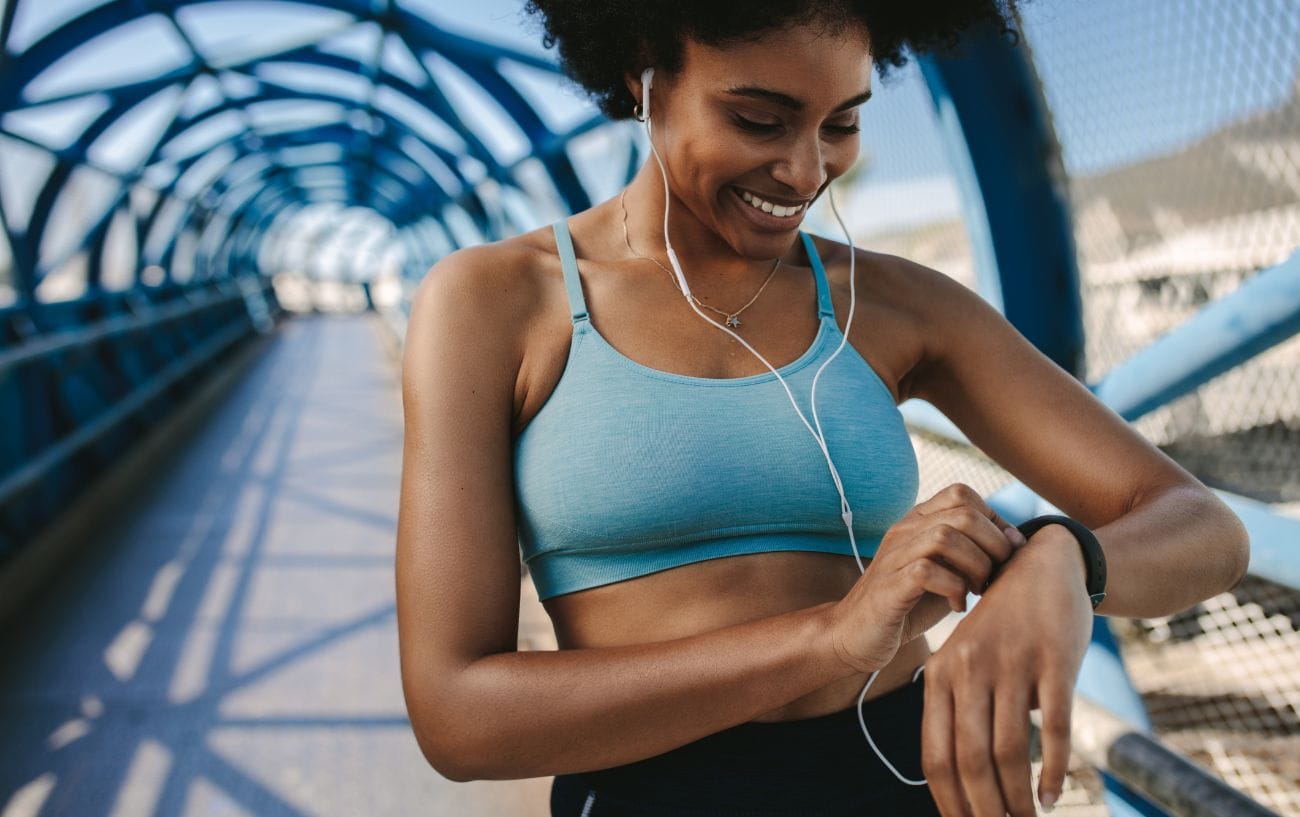 Can I Run a Half Marathon? Here’s How to Know If You’re Ready 2 a woman wearing headphones looking at her watch