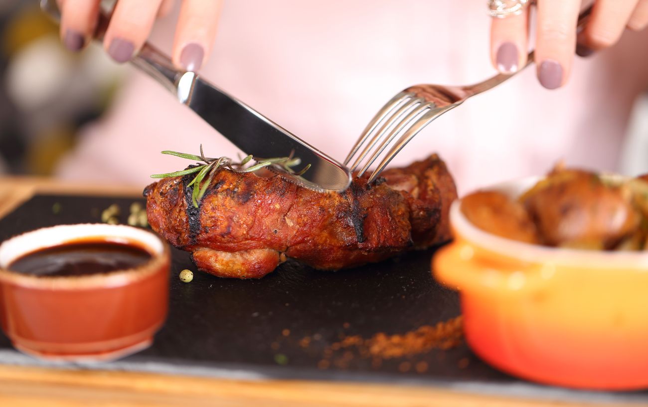 Una persona comiendo un bistec.