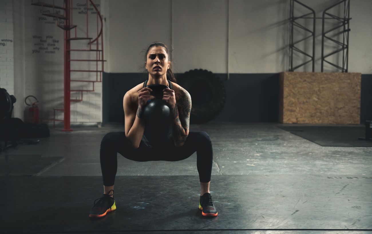 Una persona haciendo una sentadilla goblet con kettlebell.