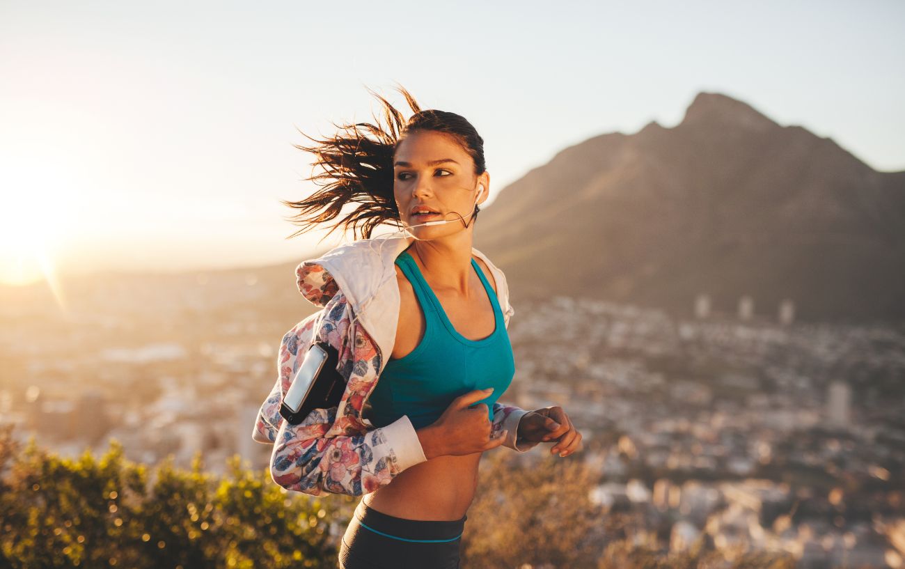 Una corredora con un sujetador deportivo, chaqueta y leggings.